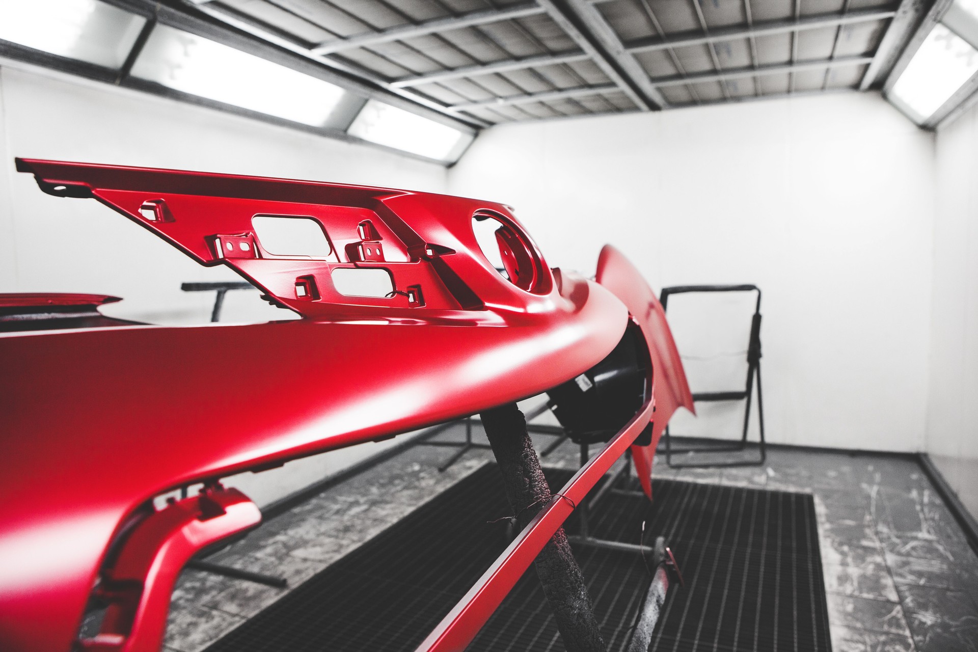 Car body element being painted in paint booth. Auto body repair.